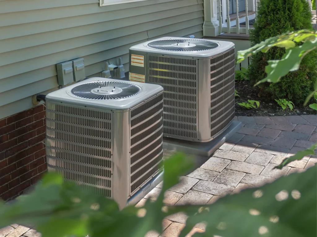 Residential air conditioning condensers installed beside a home