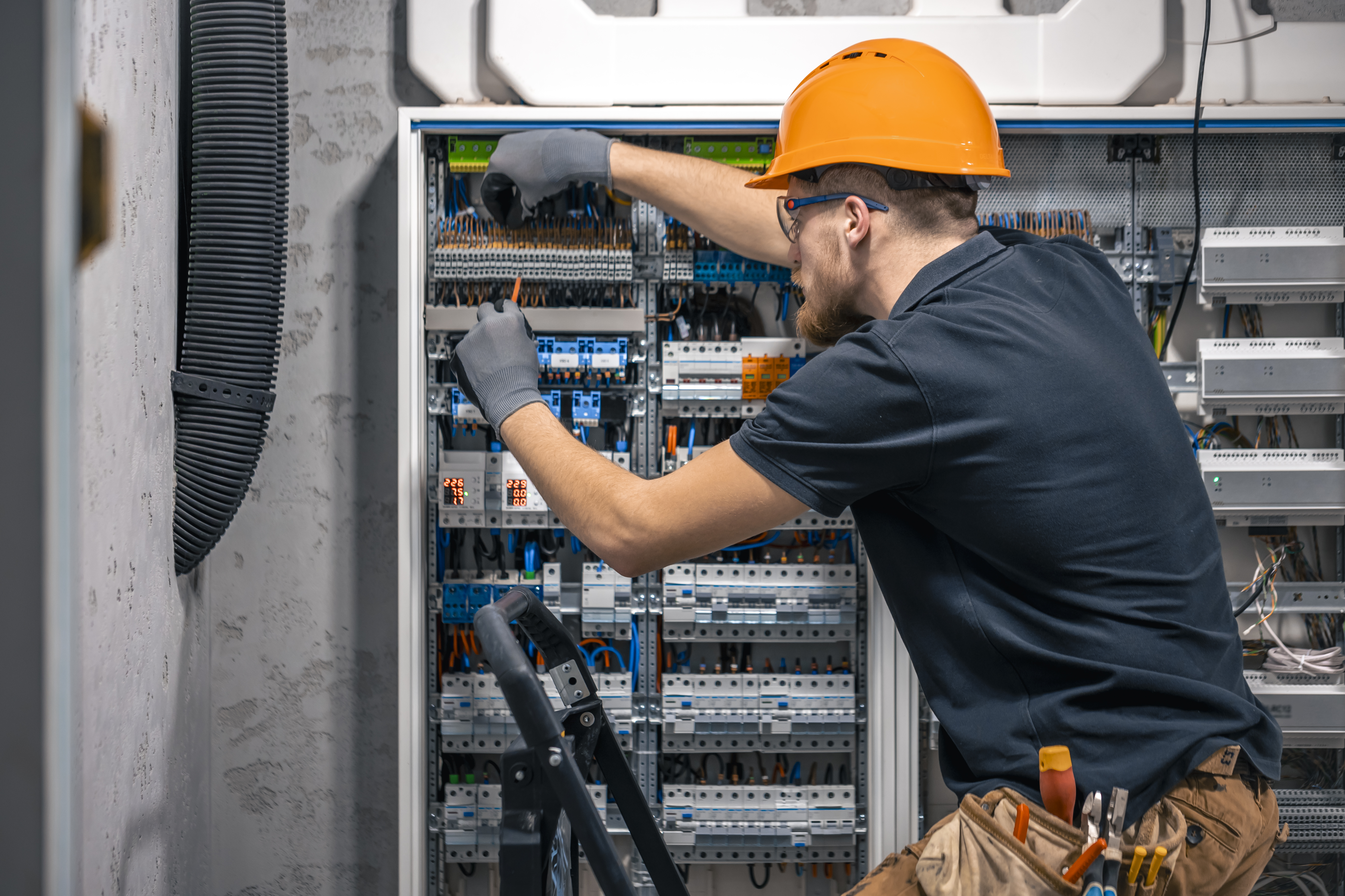 Technician servicing an electrical control panel for HVAC and refrigeration equipment